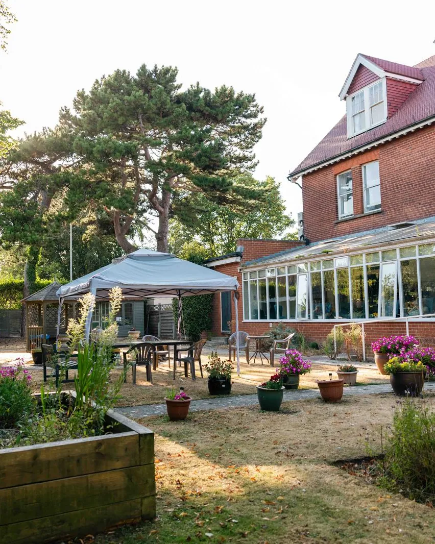 The garden at Wraysbury House, with raised beds, a gazebo and a conservatory along the back of the house